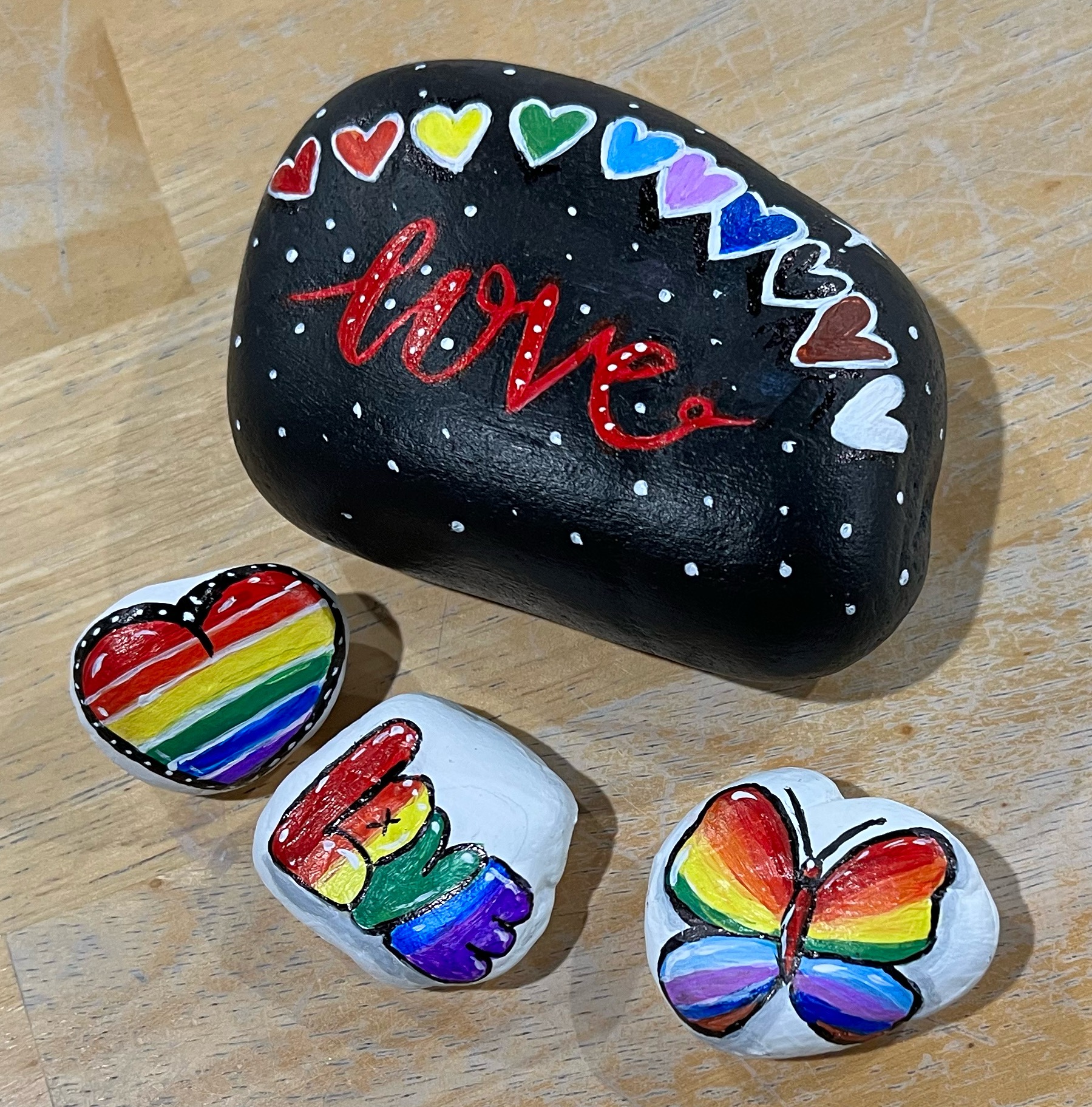 Image of a few rocks painted with pride colors and rainbows.